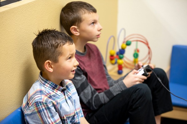 Two boys playing video games on couch.
