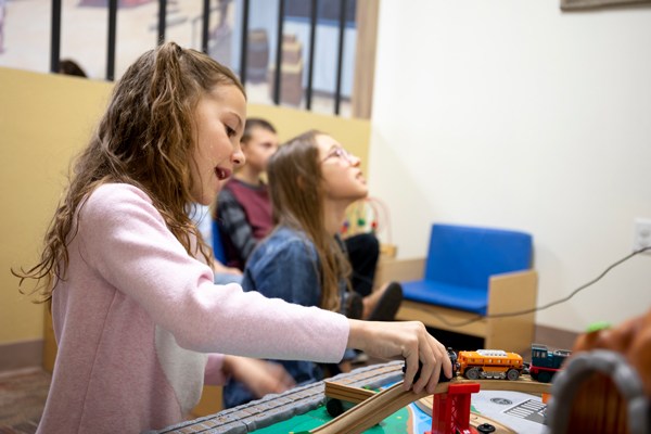 Children playing with toy train set indoors.
