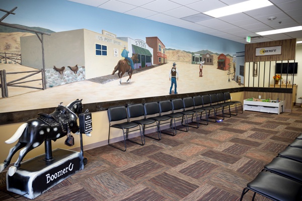 Western-themed mural in waiting room with chairs.