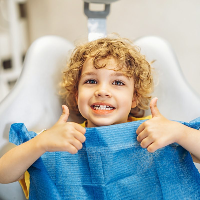 Happy child giving thumbs up at dentist