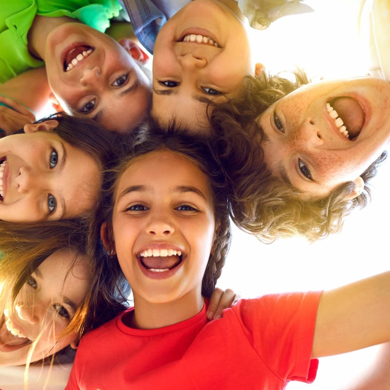 Happy kids smiling in a circle outdoors.