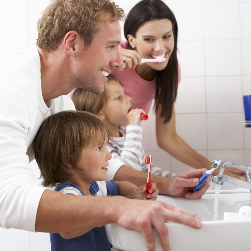 Family brushing teeth together in bathroom
